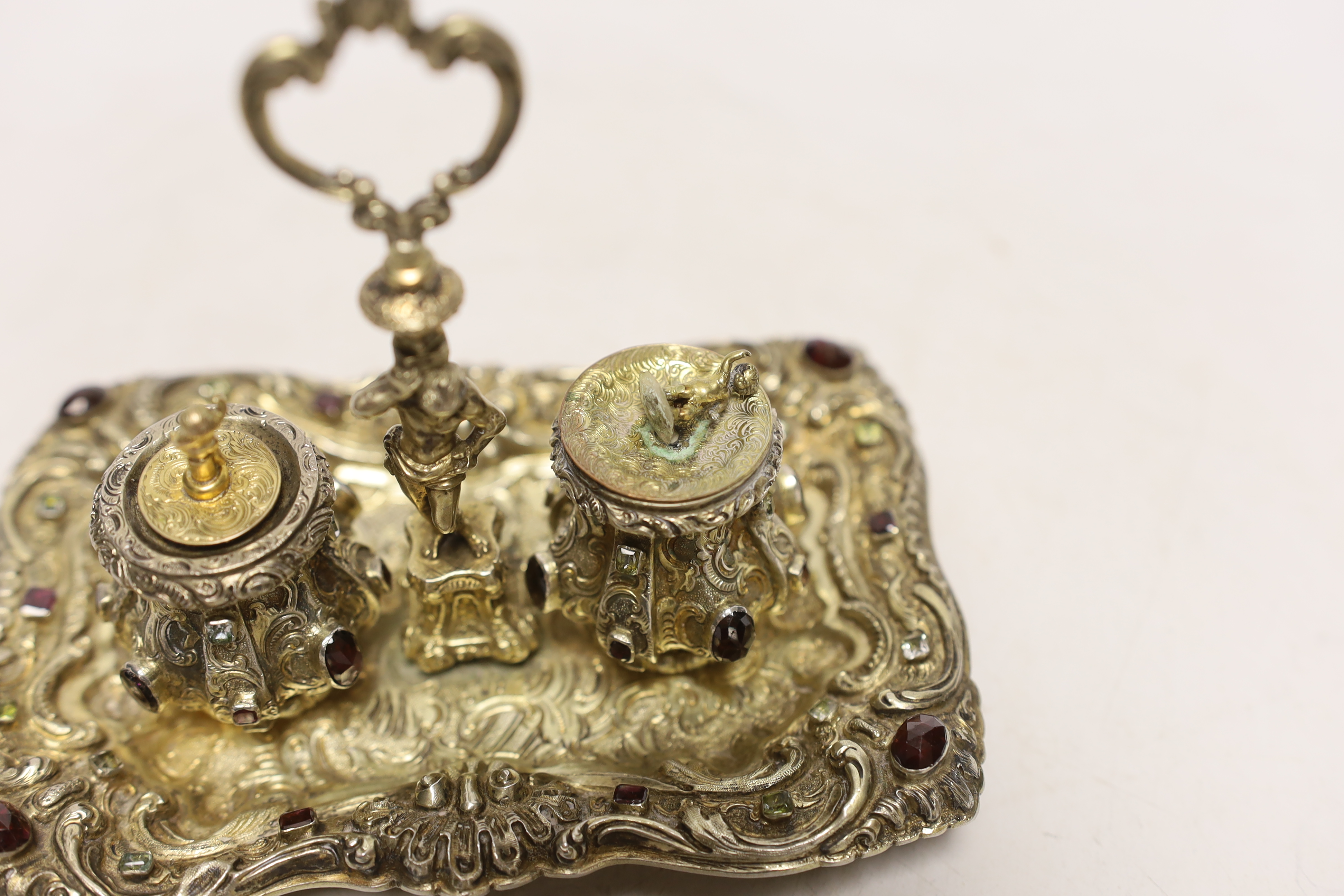 A 19th century Austrian embossed gilt white metal and multi gem set rectangular inkstand, with ring handle and two wells, 14.2cm, gross weight 6.3oz (a.f.).